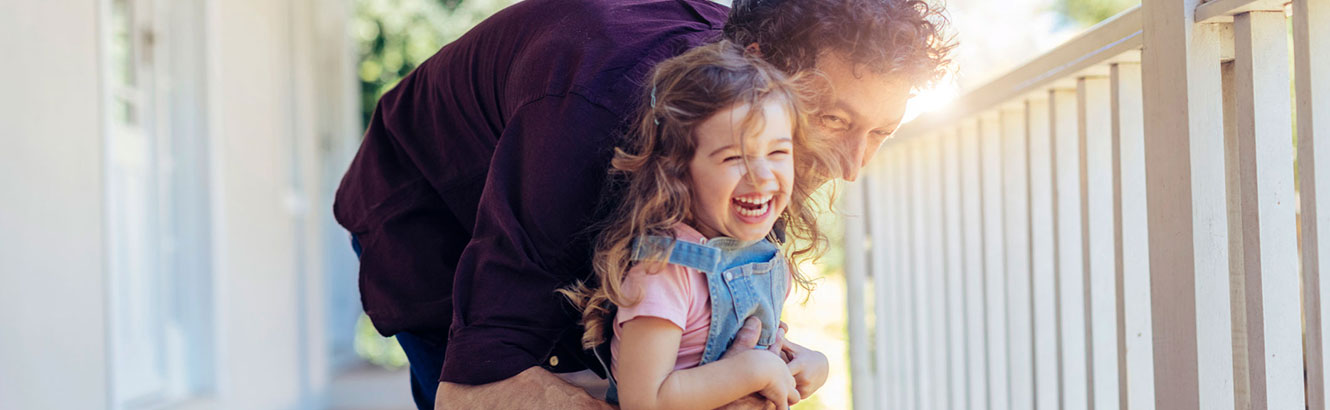 Dad playing with his daughter on their front porch.